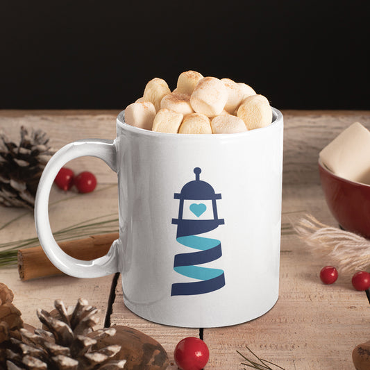 Tasse blanche avec le logo Simplement Humain, remplie de guimauves, posée sur une table en bois décorée d'éléments festifs comme des pommes de pin, des baies rouges et des épices.