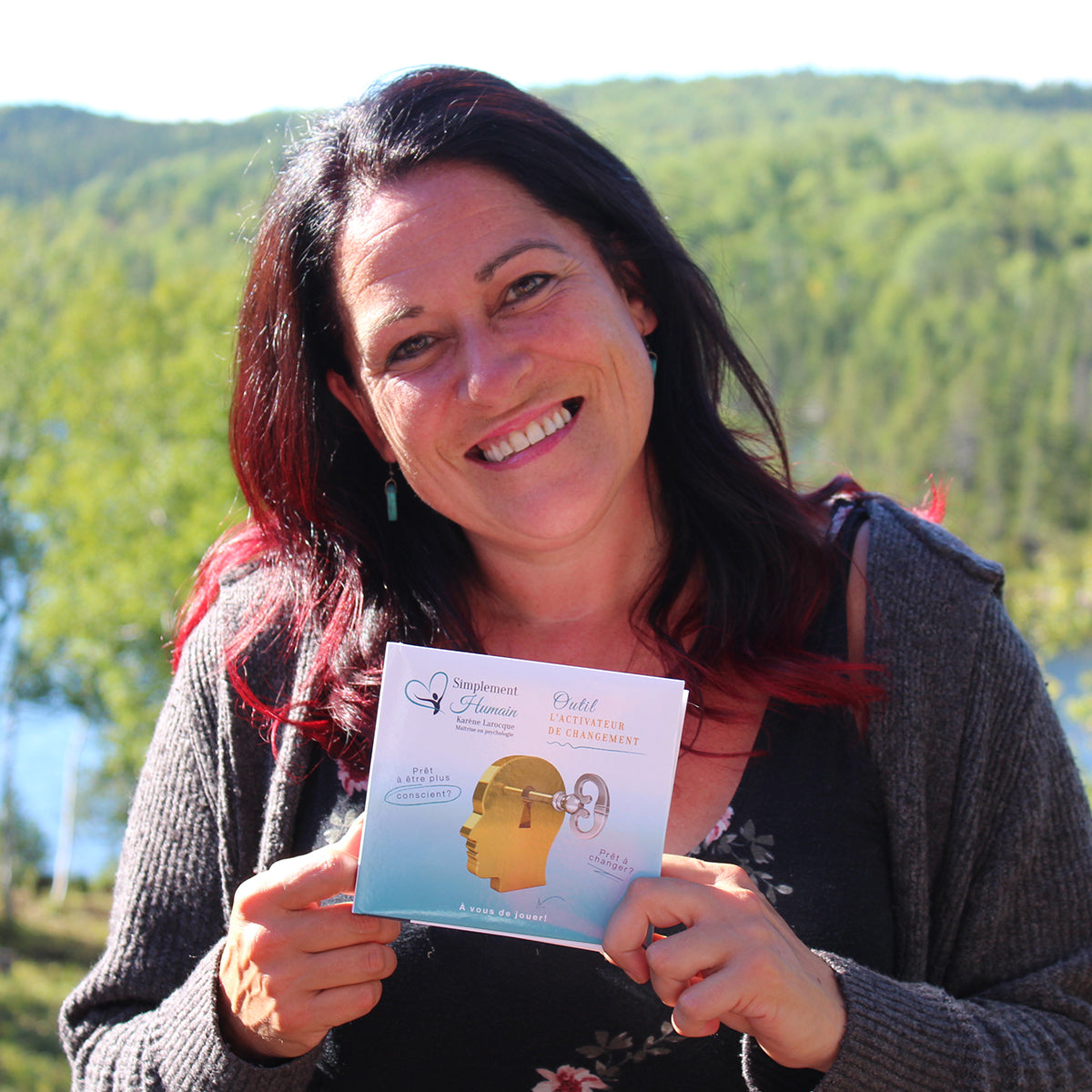 Karène Larocque, créatrice de Simplement Humain, souriante en plein air, tenant l'Activateur de changement. Un outil pour mieux se comprendre et avancer vers ses objectifs.